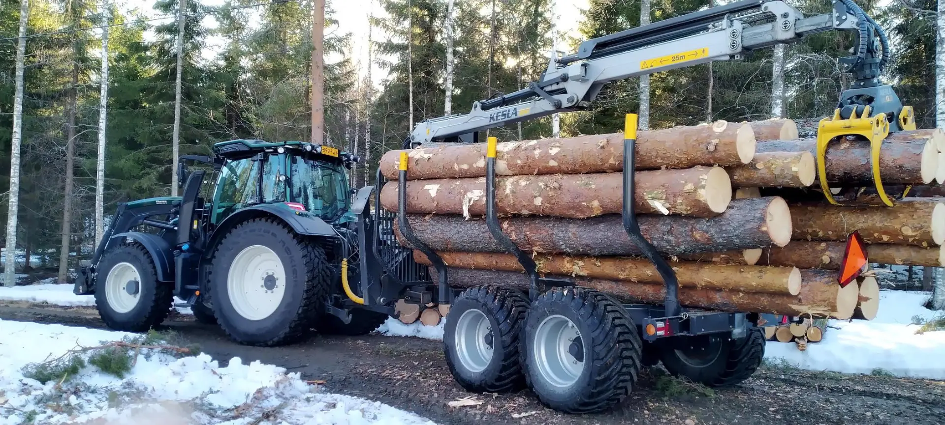 Traktori ja metsäperävaunu puunrunkojen poisajossa